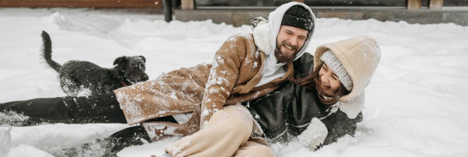 Couple s&rsquo;amusant dans la neige devant un chalet lors d&rsquo;un week-end romantique en location dans les Alpes