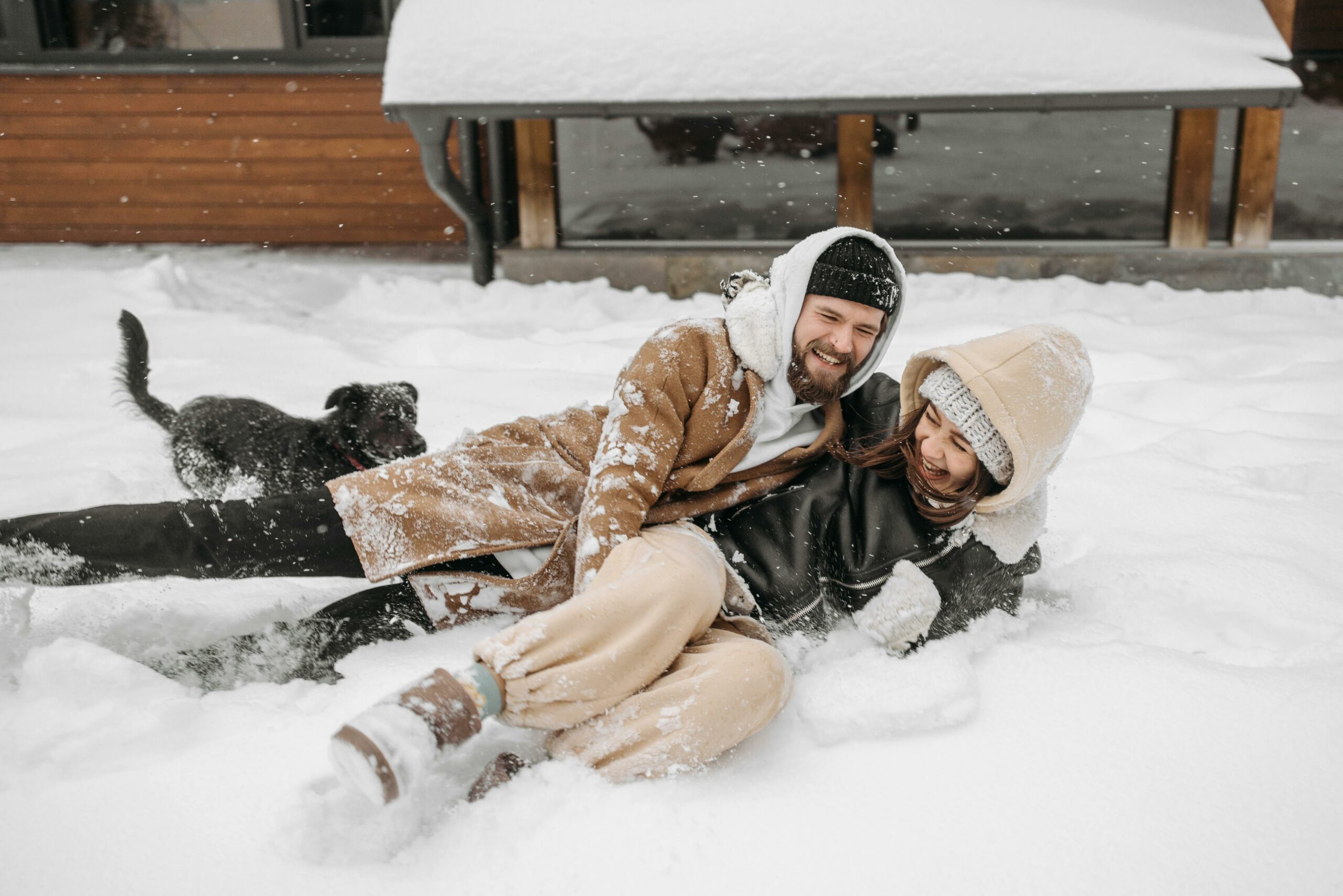 Couple s&rsquo;amusant dans la neige devant un chalet lors d&rsquo;un week-end romantique en location dans les Alpes